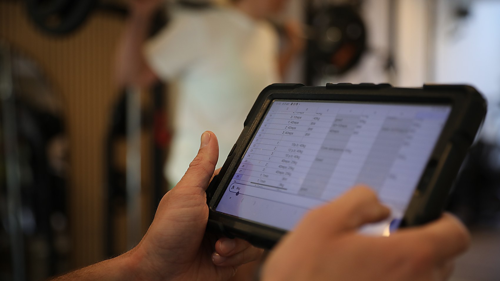 A MudaGym coach reviewing a client's personalised training programme on a tablet